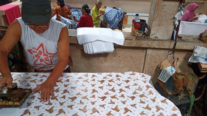 Seorang perajin tengah mengecap pola saat produksi kain batik bermotif dua jari di Batik Putra Laweyan, Kampung Batik Laweyan, Kecamatan Laweyan, Solo, Jumat (8/3/2019).