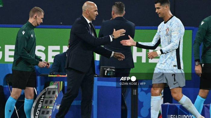 Pelatih kepala Portugal Roberto Martinez berjabat tangan dengan penyerang Portugal #07 Cristiano Ronaldo saat ia meninggalkan lapangan untuk diganti selama pertandingan sepak bola Grup F UEFA Euro 2024 antara Georgia dan Portugal di Arena AufSchalke di Gelsenkirchen pada 26 Juni 2024.