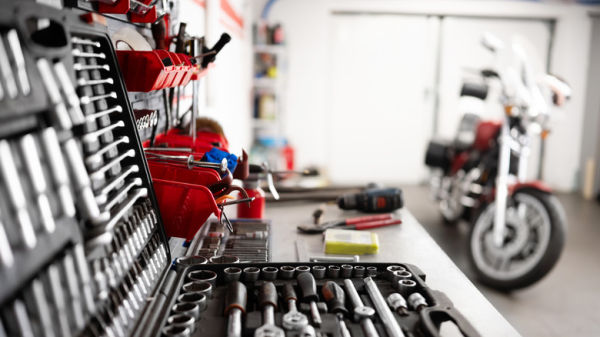 Close up of tools on a garage work bench with motorcycle in the background.