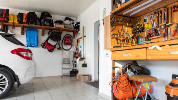 Inside view of garage with organized work bench and white car parked nearby.