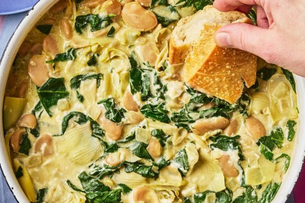A recipe image of Creamy Spinach & Artichoke Dip Butter Bean Skillet. Credit: Photographer: Greg Dupree, Prop Stylist: Julia Bayless, Food Stylist: Chelsea Zimmer.