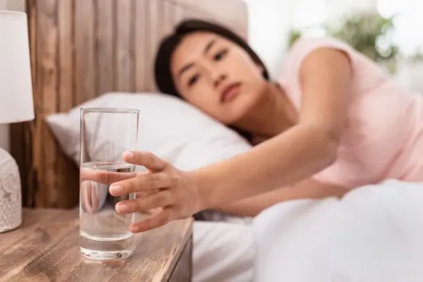 Healthy Liquid. Asian Lady Drinking Water From Glass Starting Day With Hydration Lying In Bed At Home. Selective Focus