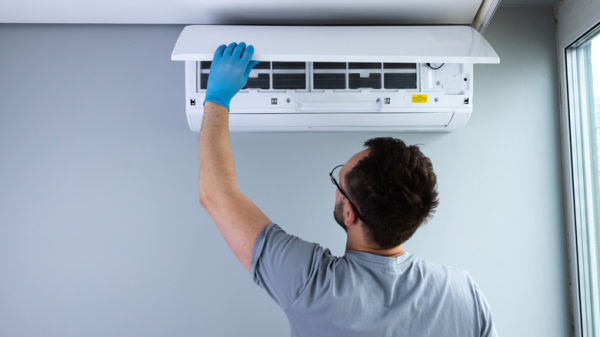 A skilled technician performing maintenance on a ceiling-mounted air conditioning unit