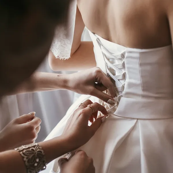 bridesmaids lacing up wedding dress