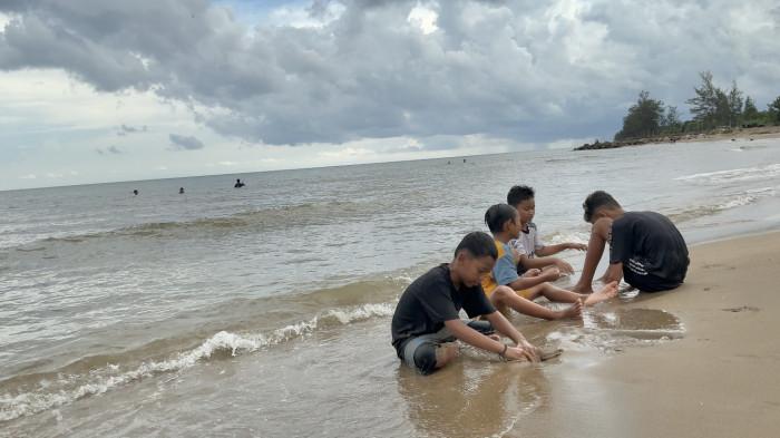 BERMAIN PASIR - Wisatawan anak-anak sedang bermain pasir di Pantai Borneo Beach Jorong, Minggu (22/3/2026). Pasir bersih jadi keunggulan pantai yang tidak jauh dari Banjarmasin itu.