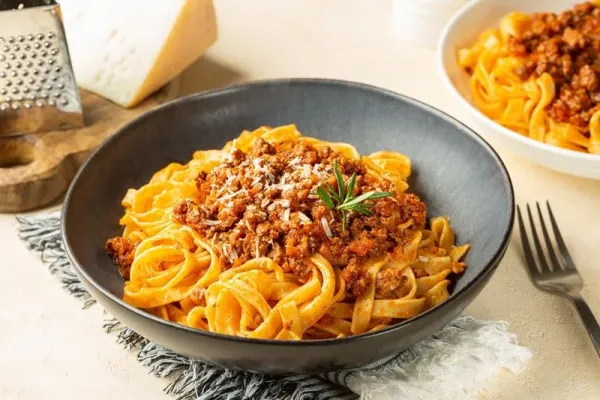Close up of plates with Tagliatelle al ragu - long, flat egg pasta with a meat sauce or Bolognese sauce and parmesan cheese, served with rosemary.