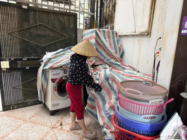 Ms. Phuong used a tarpaulin to cover 6 washing machines and dryers placed in front of her family's yard at her home in alley 12 Chinh Kinh street, Thanh Xuan ward, on the morning of May 19. Photo: Quynh Nguyen