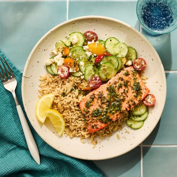 a recipe photo of Lemony Salmon Rice Bowl with Feta, Cucumber & Tomato Salad Credit: Photographer: Victor Protasio, Food Stylist: Chelsea Zimmer, Prop Stylist: Hannah Grennwood.
