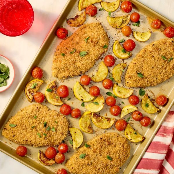 a recipe photo of Sheet-Pan Crispy Chicken with Squash & Tomatoes Credit: Photographer: Robby Lozano, Food Stylist: Giovana Vazquez, Prop Stylist: Keoshia McGhee