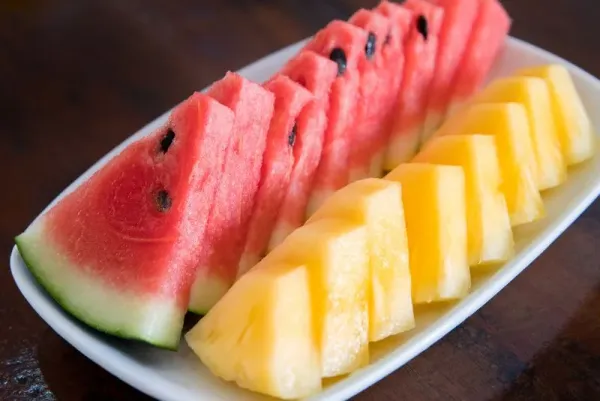 Watermelon and pineapple slices on a wood ceramic plate
