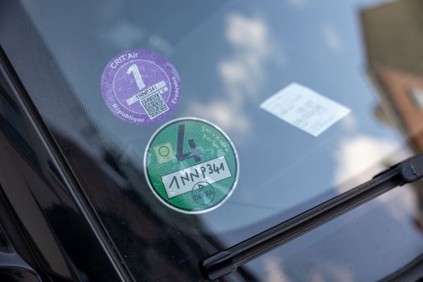 Car windshield displaying crit'air and umweltplakette emission stickers