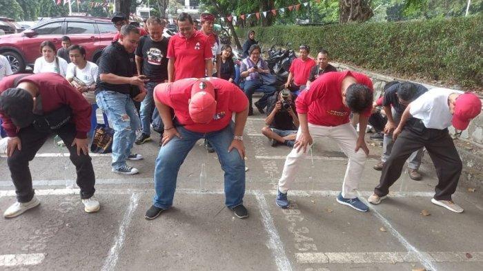 Peserta lomba 17 Agustusan Pers Gas Tipis Tipis sedang berusaha memasukkan pensil ke dalam botol