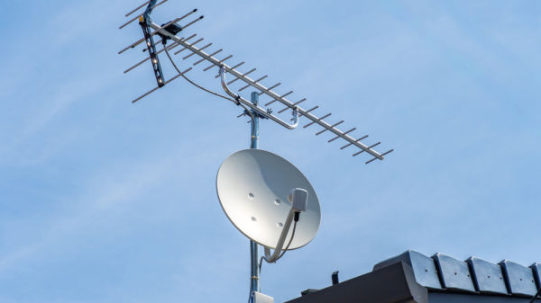 A TV antenna and satellite dish installed on the rooftop of a building