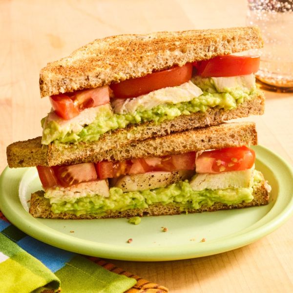 A sandwich made with avocado tomato and chicken sliced in half and served on a plate Credit: Photographer: Stacy K. Allen, Food Stylist: Jennifer Wendorf, Prop Stylist: Phoebe Hausser