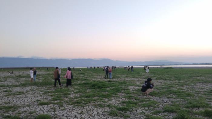 DANAU LIMBOTO - Suasana senja di Danau Limboto pada Senin (10/8/2026). Masyarakat datang berswafoto bersama keluarga hingga kerabat. (Sumber foto: TribunGorontalo.com/Sandri Mooduto)