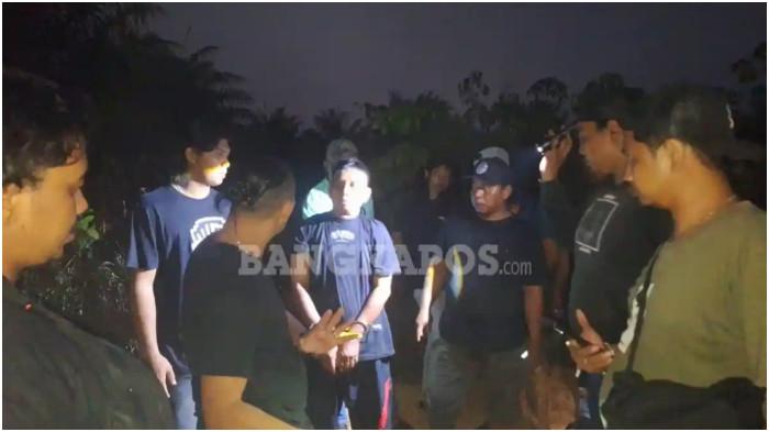 MAYAT DI DESA KACE -- Pelaku EW dengan dikawal ketat anggota polisi, ketika mendatangi lokasi tempat ia menganiaya dan mencuri barang-barang korban, Minggu (30/8/2026).