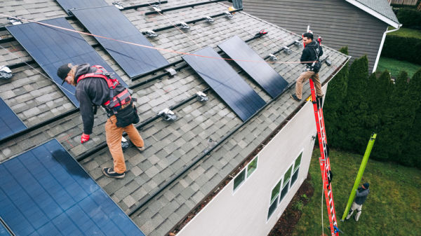 Workers installing solar panels on a roof