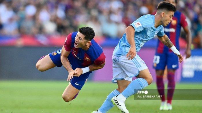 DUEL BARCELONA VS CELTA VIGO (ARSIP) - Penyerang Barcelona asal Polandia, Robert Lewandowski terjatuh saat berebut bola dengan gelandang Celta Vigo, Fran Beltran di Estadi Olimpic Lluis Companys di Barcelona pada Sabtu (24/9/2023). Jika menang atas Celta Vigo, aroma gelar juara semakin tercium El Barca. (Pau BARRENA / AFP)