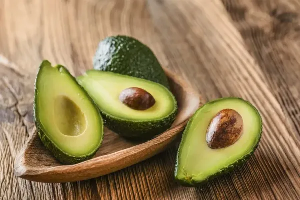 Ilustrasi buah alpukat Avocado on old wooden table in bowl. Halfs of avocados fresh fruits healthy food.