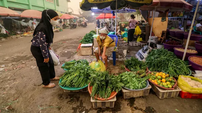 Seorang perempuan mengenakan masker saat membeli sayuran di pasar tradisional di tengah kabut asap tebal akibat kebakaran hutan dan lahan di Palangkaraya, Kalimantan Tengah, Senin (12/10/2026). Kabut asap menyelimuti sejumlah wilayah di Indonesia, Malaysia, dan Singapura selama beberapa pekan terakhir akibat kebakaran yang melanda kawasan hutan di Kalimantan dan Sumatra. Asap kebakaran terbawa angin hingga melintasi wilayah regional dan berdampak pada kualitas udara. (REINA/AFP)
