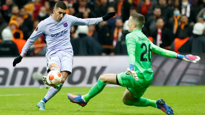 Penyerang Barcelona Ferran Torres (kiri) melakukan tembakan di depan kiper Galatasaray Inaki Pena pada leg kedua 16 besar Liga Europa di NEF Stadyumu, Jumat (18/3/2022) dini hari WIB. Hasil Galatasaray vs Barcelona berakhir dengan skor 1-2. (KEMAL ASLAN / AFP)
