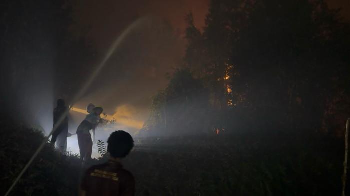 KARHUTLA - Sejumlah relawan dan tim satgas Pesantren Intan Ilmu saat memadamkan kobaran api yang berkobar di lahan dekat pesantren, Senin (12/10/2026) malam.