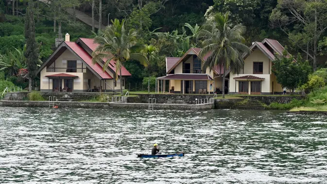 Danau Toba Nelayan mendayung melewati penginapan bernuansa resort di Pulau Samosir, di tengah Danau Toba, Sumatra Utara, 3 April 2019. Danau berkawah seluas 1.145 kilometer persegi ini diperkirakan terbentuk dari letusan supervolcano Gunung Toba yang terjadi sekitar 74.000 tahun lalu. (GOH CHAI HIN / AFP)